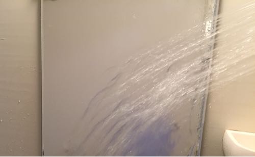 汚れた鏡にシャワーをかけている